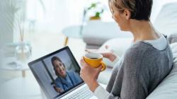 Person sitting on a couch with a laptop on their lap speaking with a healthcare professional virtually