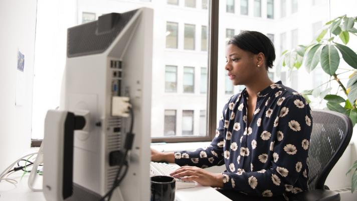 A female patient navigator sits at her desk working on a desktop.