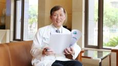 China Medical University Hospital Superintendent Dr Der-Yang Cho sitting on a chair while holding a paper report