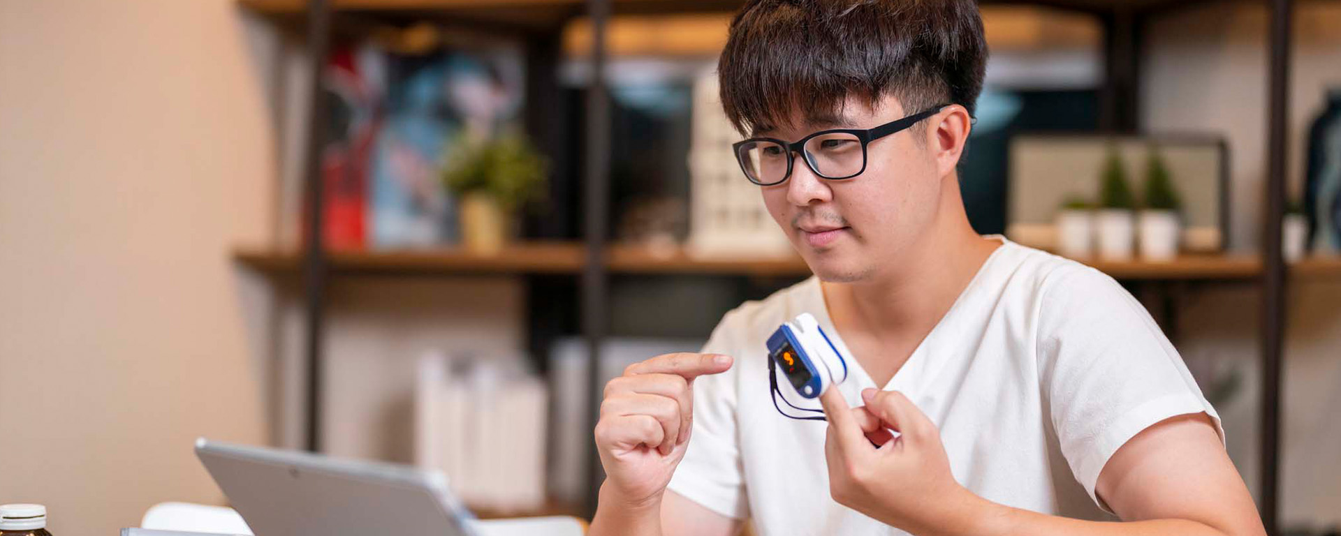 Person in front of laptop with remote medical device on finger