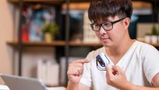 Person in front of laptop with remote medical device on finger