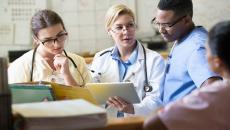 Clinicians discussing around a nurses' station.