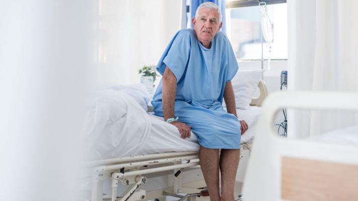 Patient sits in a patient gown in a medical exam room