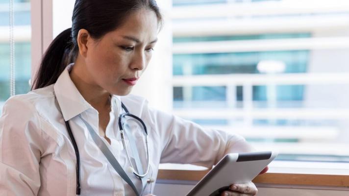 A doctor checking a patient's record on a digital tablet