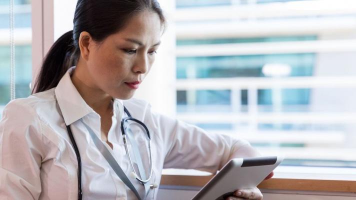 A doctor checking a patient's record on a digital tablet