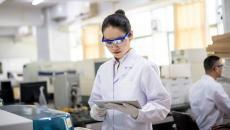 Female clinical researcher in a lab looks at a tablet