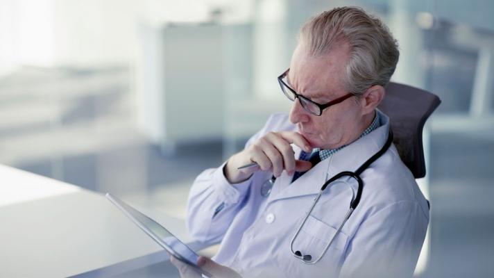 A doctor reading from a digital tablet.