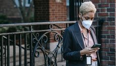 Woman in mask checks smartphone for update